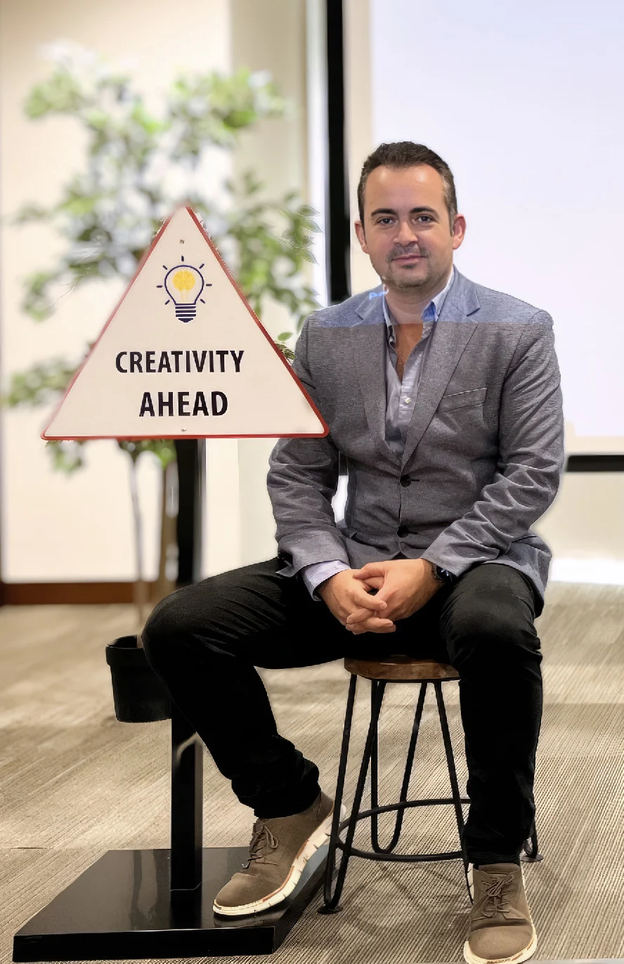 Marc Mekki seated beside a Creativity Ahead sign
