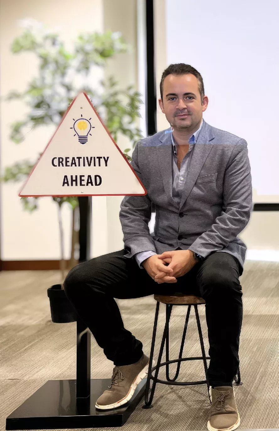Marc Mekki seated beside a Creativity Ahead sign